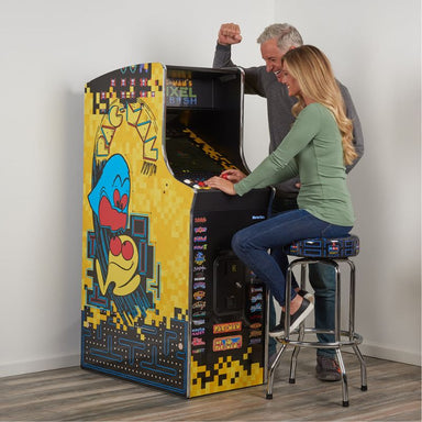 Two people playing a vintage-style Pac Man arcade game together.