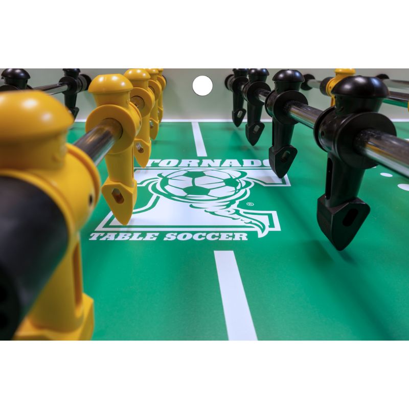 Close-up of a Tornado table soccer game with yellow and black players on a green field.