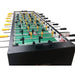 Close-up of a foosball table with green playing surface and black and yellow rods.